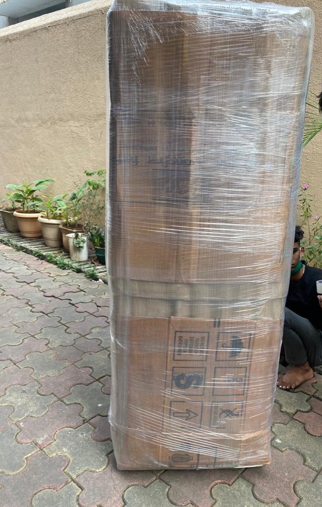 Large appliance wrapped in cardboard and plastic with shipping marks, ready for relocation